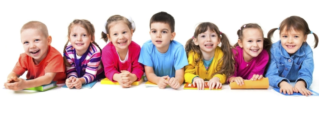 A group of young kids lying on the floor, smiling brightly.