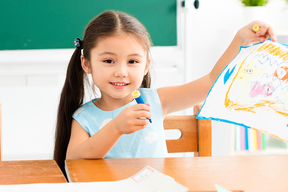 Girl showing her drawing in a classroom.