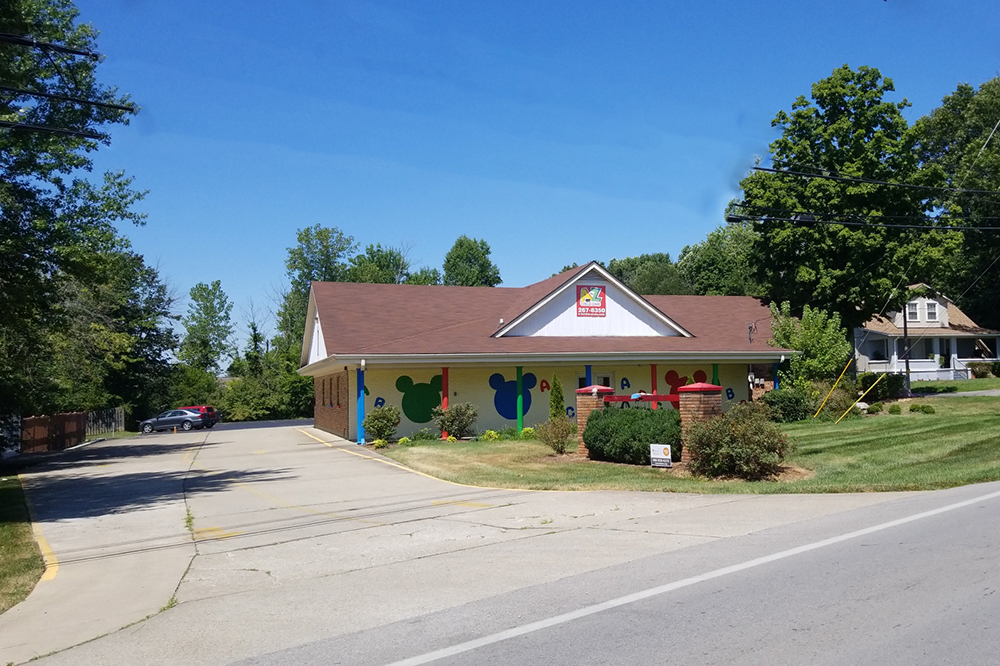 A single-story childcare building with colorful shapes painted on the walls and a driveway out front.
