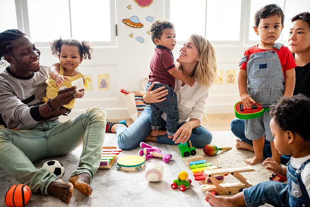 Toddlers and teacher playing with toys on the floor.